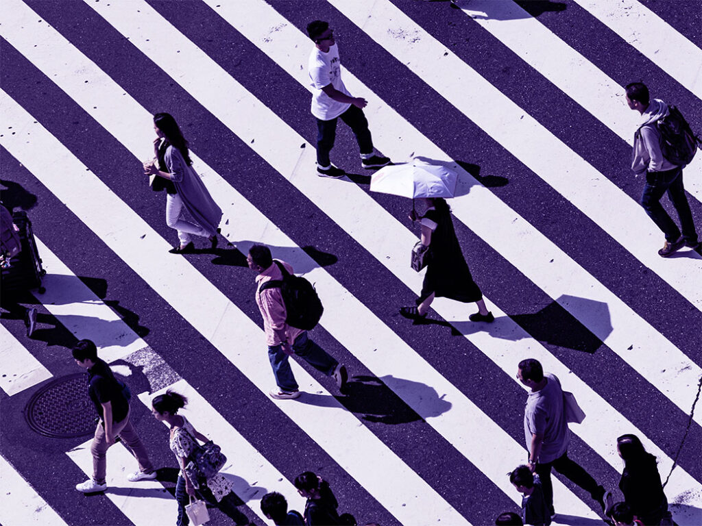 Aerial shot of people walking fast over large diagonal pedestrian crossing
